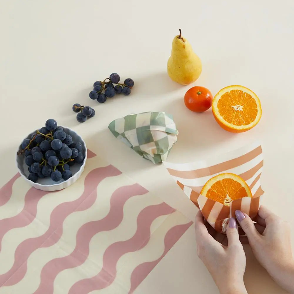 An assortment of fruit being wrapped in colorful paper.