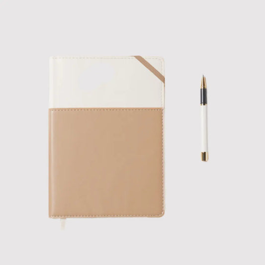 The Journal + Pen Bundle (Ivory + Oat) features a beige and white vegan leather journal with a matching pen, crafted from sustainable, eco-friendly materials and shown on a plain light background.