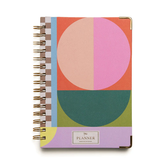The 13 Mo Perpetual Planner - Geo Checks is a durable wire-bound organizer with a hardcover in bold geometric patterns and vibrant pink, orange, green, and purple hues, plus gold corner accents—ideal for anyone who wants a standout, stylish planner.