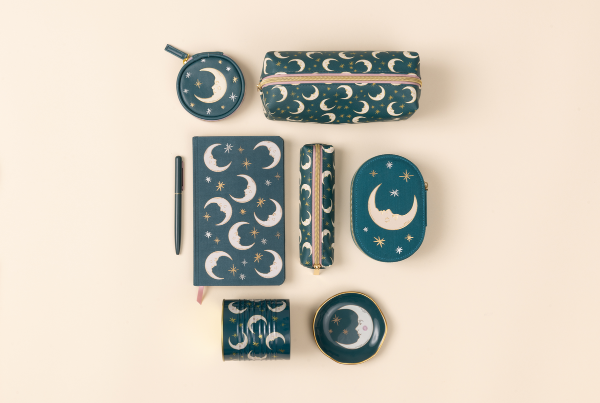 Collection of blue stationery items with moon and star designs on a beige background