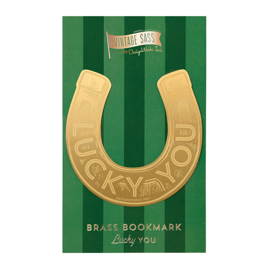 The Vintage Sass Brass Bookmark - Lucky you features a gold-finished brass horseshoe shape, presented on a green striped card with LUCKY YOU—a modern take on classic vintage bookmark style.
