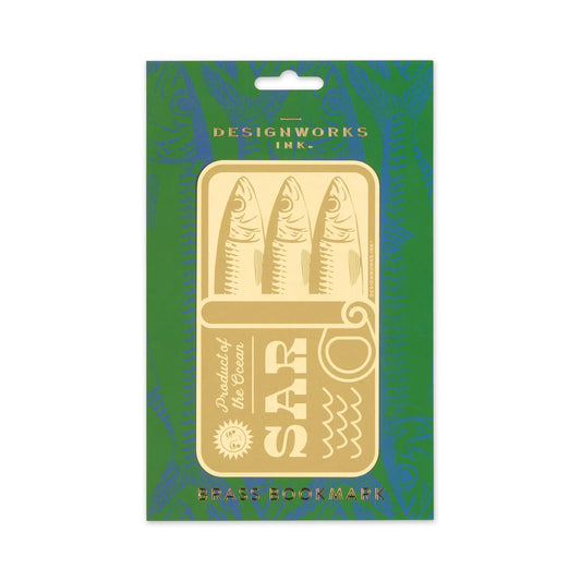 The Brass Bookmark - Sardines features a sardine can shape with three fish, adding sophistication to your reading. Presented on green packaging labeled Designworks Ink. and Brass Bookmark.