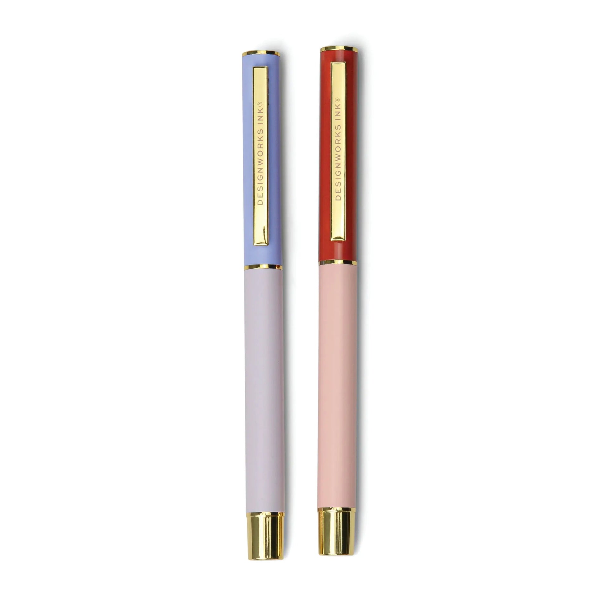 The Color Block Pens - Lavender + Blush set features two matte-finish ink pens with gold clips and tips—one in lavender/light blue, one in pink/red. Both pens have DESIGNWORKS INK engraved on the clip for an elegant touch.