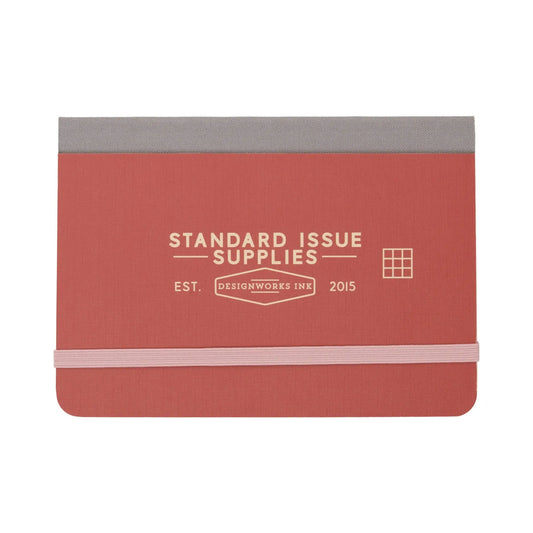Standard Issue Pocket Journal - Rosewood + Blush by Designworks Ink features an elastic closure, grid pages, and a rectangular grid icon on the cover—perfect for travel notes.
