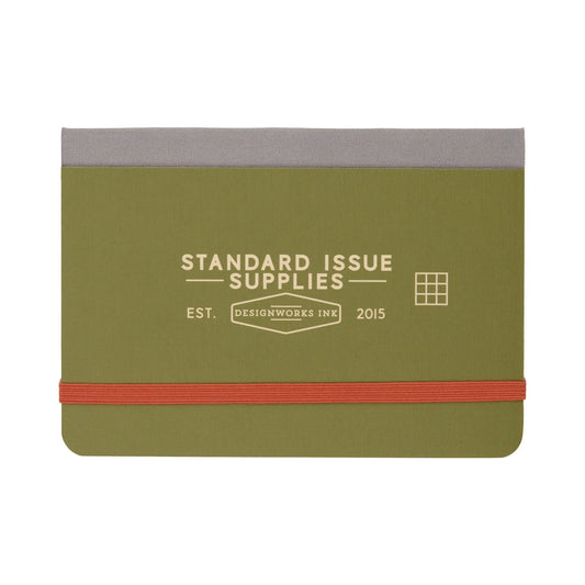 The Standard Issue Pocket Journal - Army Green + Chili is a compact green and gray notebook with Standard Issue Supplies and Designworks Ink on the cover, an orange elastic band, and a convenient grid format.