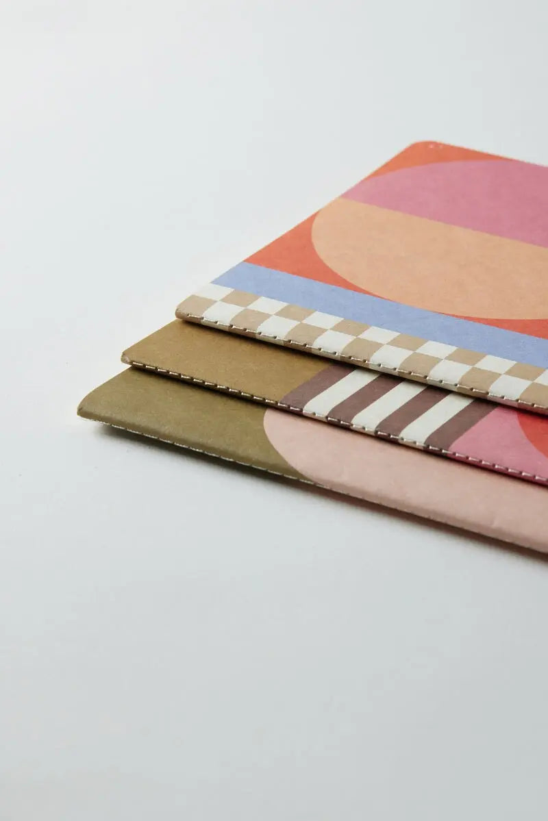 A set of three Flex Notebooks with a saddle stitch spine in the Mod Geo design is stacked on a plain white surface.