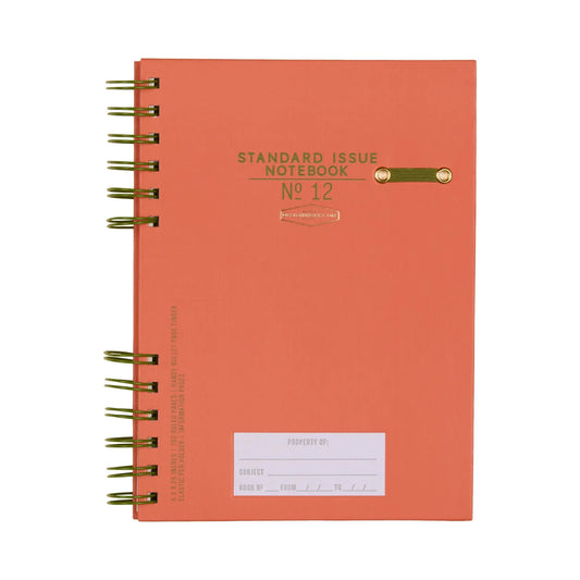 The Standard Issue Planner Notebook No. 12 in Army Green + Chili is spiral-bound and designed for premium writing, featuring durable construction, a gold clasp, and a white property label on the front cover.