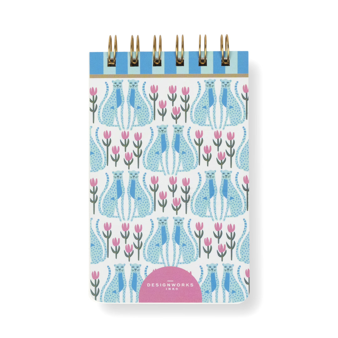 The A Dopo Blue Cheetah Twin Wire Notepad is a small, compact notepad featuring a stylish blue cheetah pattern on the cover, accented with pink details and leaves. A pink semicircle at the bottom displays white “DesignWorks Ink” text, making it an ideal choice for anyone seeking chic and eco-friendly stationery.