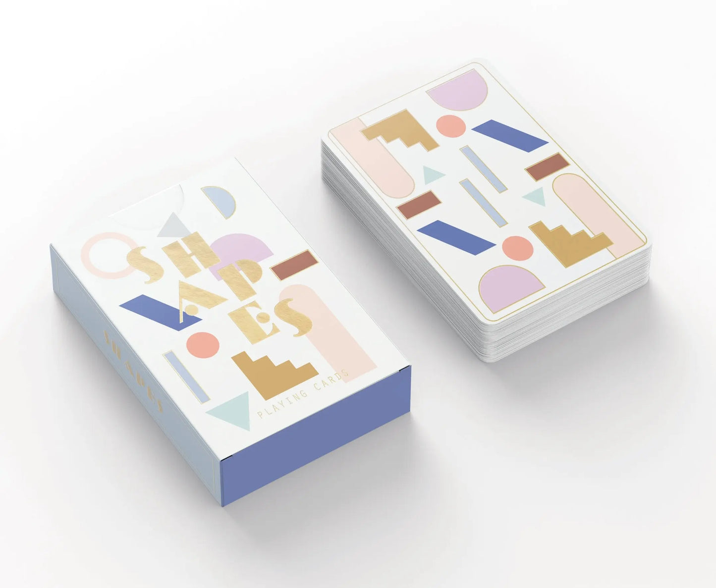 The Playing Cards - Shapes deck and box feature abstract geometric shapes in pastel colors with gold foil accents, displayed on a white surface.