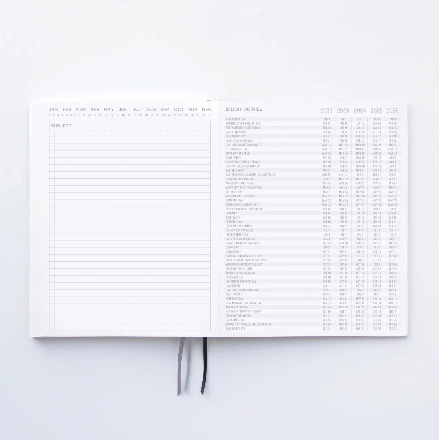 An open Standard Issue Notebook No.3 - Green shows a lined notes page on the left and holidays from 2022–2026 on the right. Two ribbon bookmarks are visible, emphasizing its quality construction.