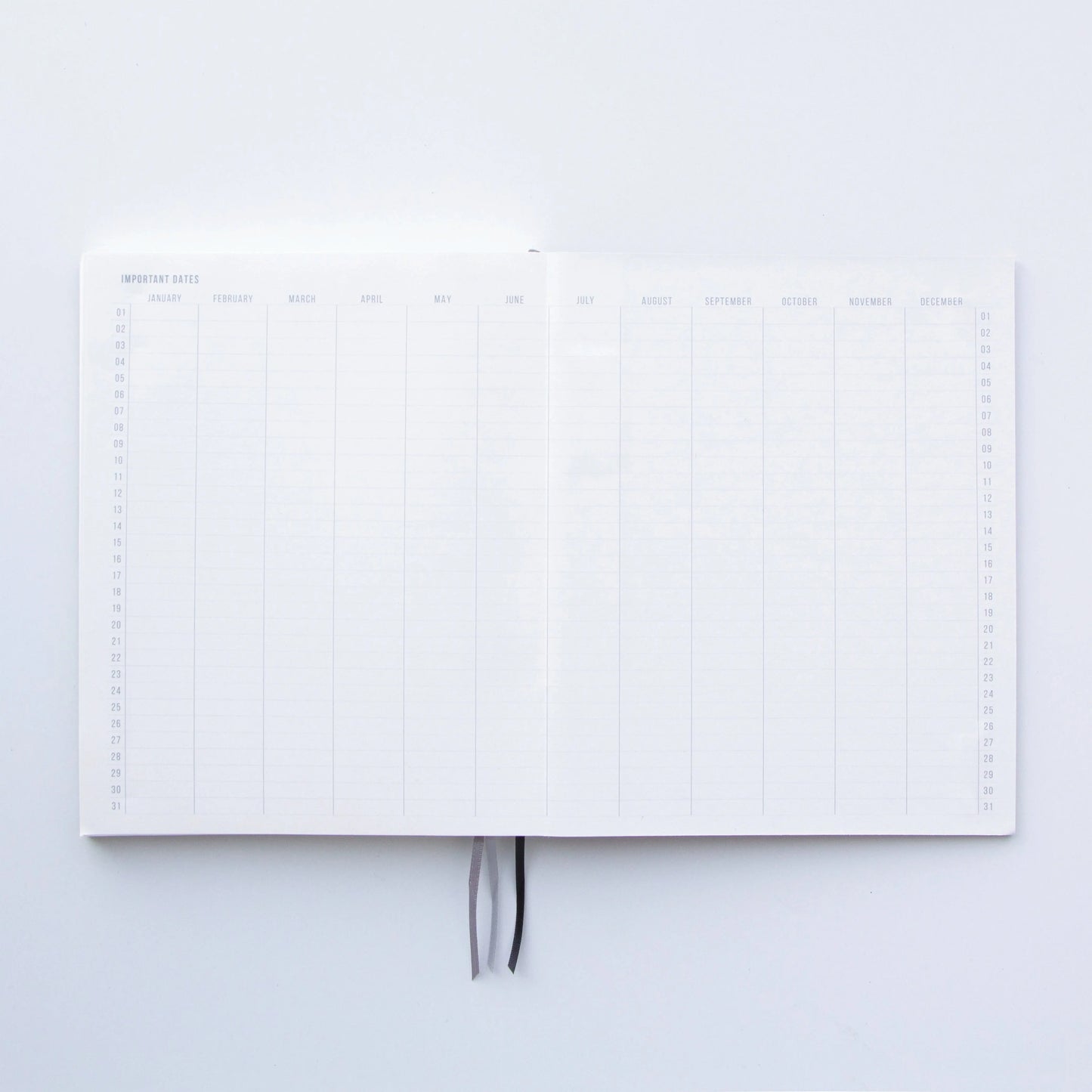 The Standard Issue Notebook No.3 - Green is open to a two-page yearly overview with monthly columns and rows for days 1–31. Two ribbon bookmarks at the center highlight its quality construction and premium writing experience.