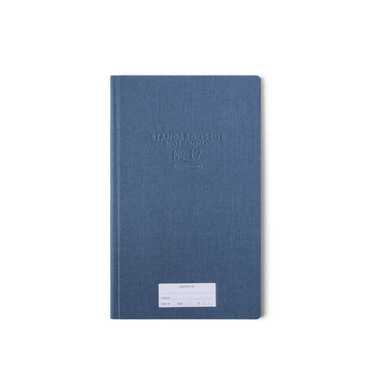 The Standard Issue Tall Notebook No.17 - Blue, featuring a durable hardcover and white label, stands out against the plain white background, highlighting the premium craftsmanship of Standard Issue notebooks.