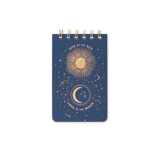 The Cloth Covered Notepad - Live By The Sun features a navy blue cover with gold sun, moon, and stars illustrations. Printed with soy inks on acid-free paper, its cover reads Live by the Sun above the sun and Love by the Moon below the moon.