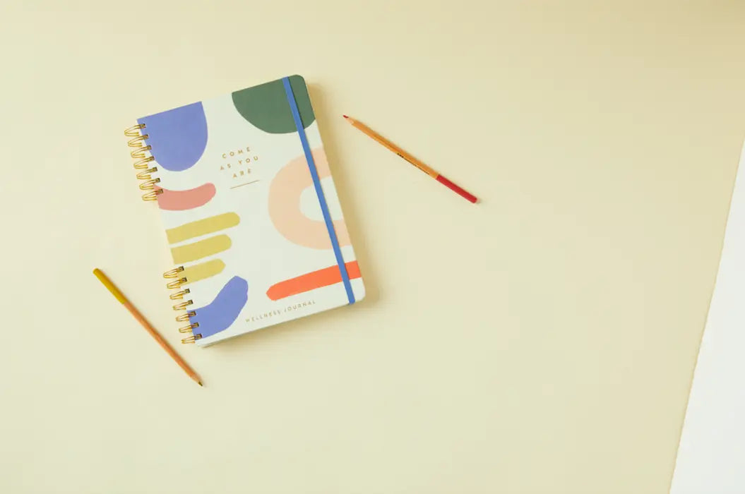 The Guided Wellness Journal - Come As You Are rests on a cream surface beside yellow and red pencils—ideal for gratitude practice or your self-care journey.