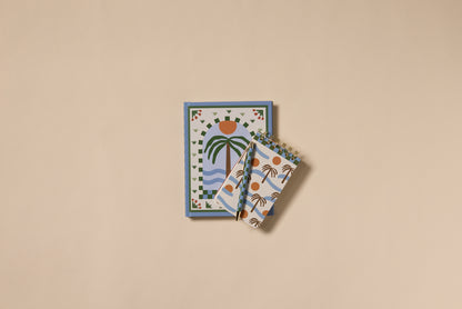 Two A Dopo Palm Twin Wire Notepads with colorful, hand-drawn palm and sun patterns—one large, one small—are arranged neatly on a beige background.