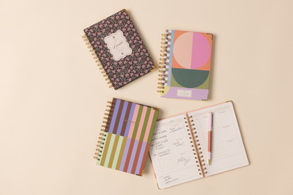 Four colorful notebooks with different designs on a beige background