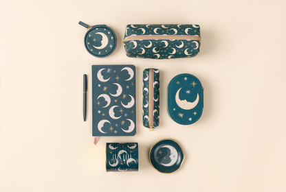 Collection of blue stationery items with moon and star designs on a beige background