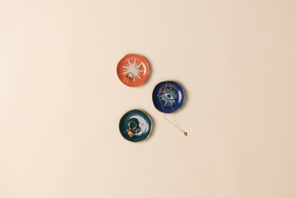 Three decorative dishes with celestial designs on a beige background