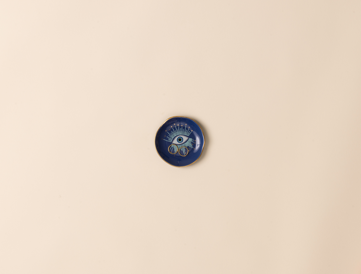 Blue decorative dish with eye design on a beige background