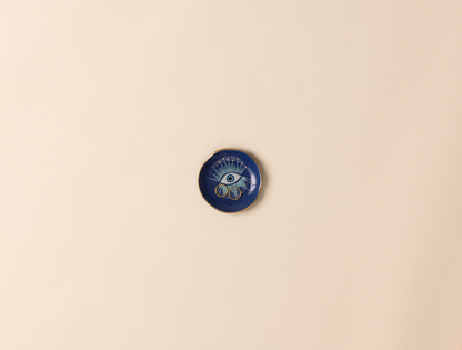 Blue decorative dish with eye design on a beige background