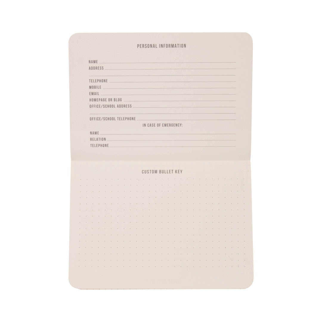 The Standard Issue Pocket Journal - Cobalt + Citron is open to reveal sections for personal information, emergency contact details, and a customizable bullet key on dotted pages. This journal features blank pages, ready to be personalized and filled in.