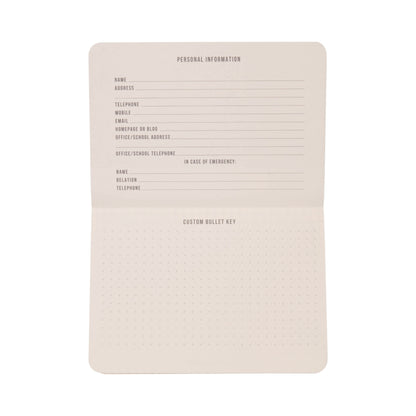 The Standard Issue Pocket Journal - Cobalt + Citron is open to reveal sections for personal information, emergency contact details, and a customizable bullet key on dotted pages. This journal features blank pages, ready to be personalized and filled in.