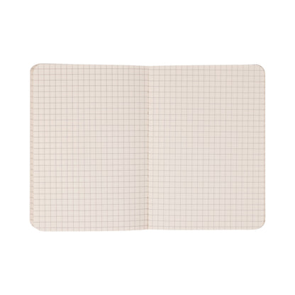 The Standard Issue Pocket Journal - Cobalt + Citron features squared graph paper pages with a precise grid of light brown lines on a white background. This travel notebook is designed with rounded corners and is photographed against a plain white surface.
