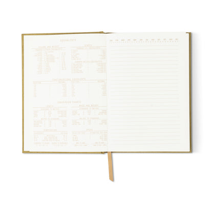 An open Radiant Journal - Avocado with a tan suede cloth cover reveals conversion charts on the left and lined pages on the right. This eco-friendly notebook includes a ribbon bookmark running down the center.