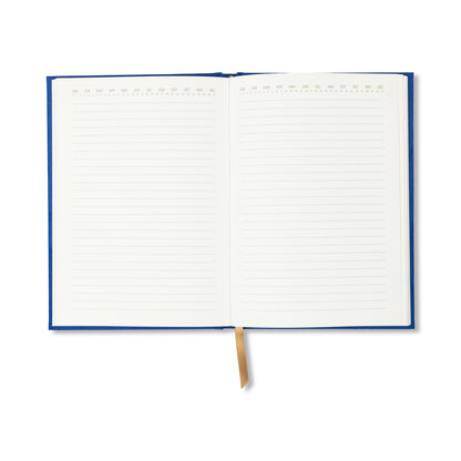 The Radiant Journal - Cobalt features a cobalt suede cover, gold ribbon bookmark, and 160 lined pages with numbered sections. Its lay-flat sewn binding lets you easily write on each page—perfect for notes or journaling.
