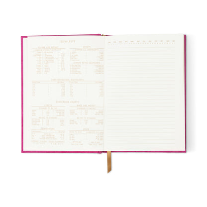 The Radiant Journal - Fuchsia features an open pink suede cover, a lined right page, and a left page printed with equivalency charts for volume, weight, and temperature. A gold ribbon bookmark is visible at the bottom.