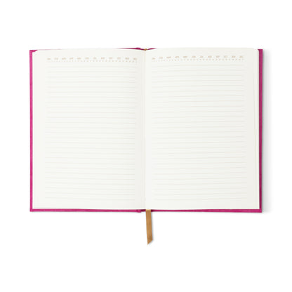 The Radiant Journal - Fuchsia is an open suede journal with a pink cover, lined pages featuring decorative top-margin numbers, and a gold ribbon bookmark in the center.