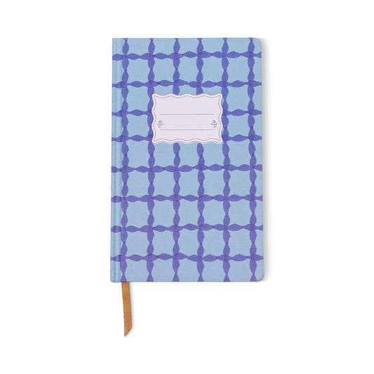The Tulip Journal - Blue Lattice features a geometric dark blue pattern, a blank white label on the cover, lay-flat binding, and a brown ribbon bookmark.