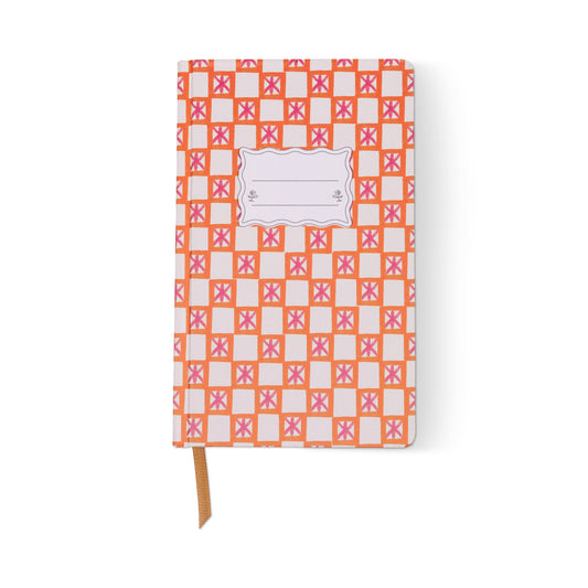 The Tulip Journal - Orange Check is a vibrant writing journal with an orange and pink geometric cover, a blank white label at the top center, orange ribbon bookmark, and a white background.