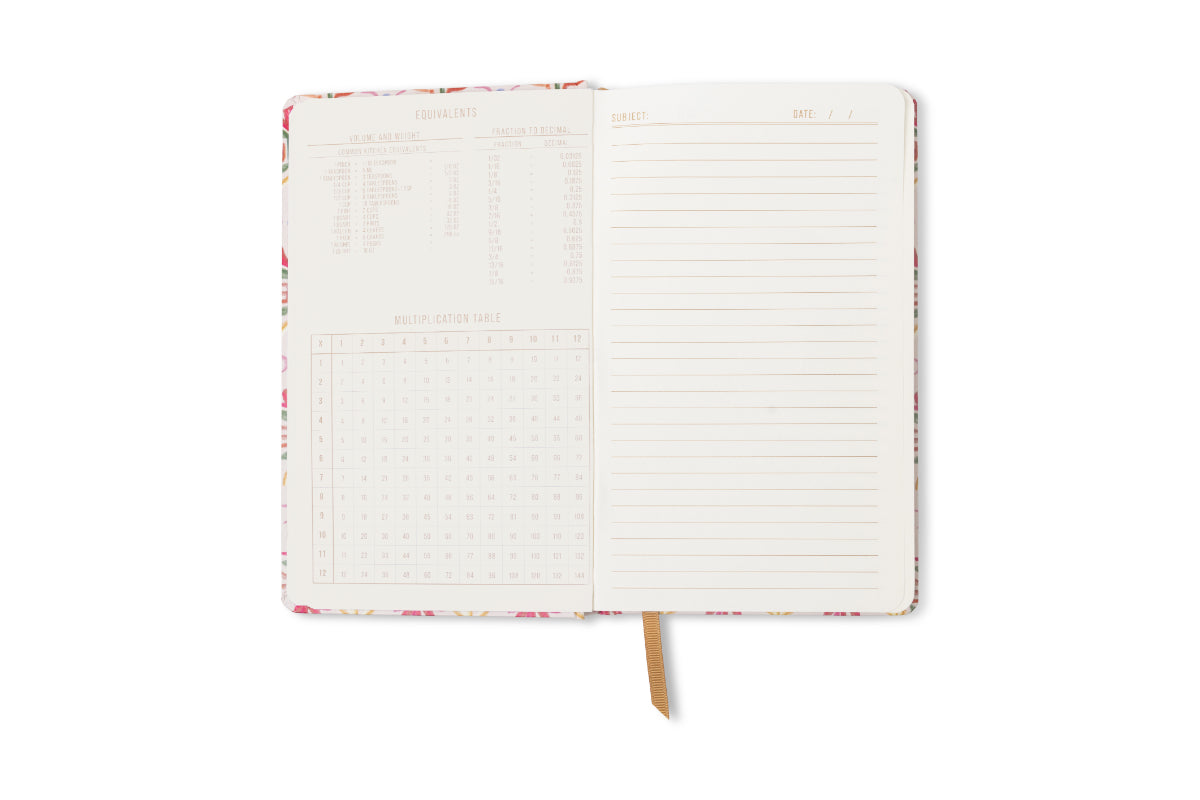 An open Tulip Journal - Tropical reveals a lined page on the right and measurement conversion charts with tables and equivalents on the left, plus a gold ribbon bookmark centered between the pages.