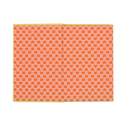 The open How To Trick People Journal features a bookcloth cover and pages adorned with a repeating wavy orange and white pattern, bordered by a yellow edge, displayed on a white background.