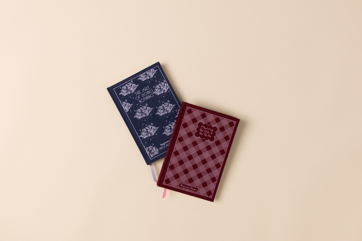 Two notebooks, one blue and one red with checkered pattern, on a beige background