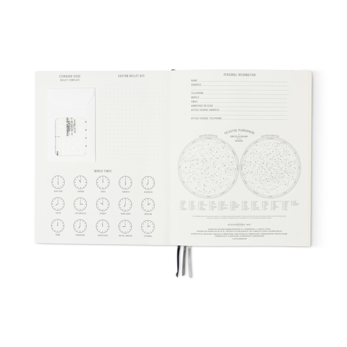 The open Standard Issue Planner Notebook No. 03 - Black reveals world time clocks, bullet key, card pocket, personal info fields, lined pages, and two celestial charts with star constellations.