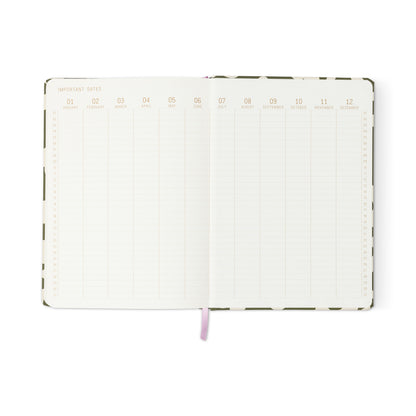The Soft Touch Jumbo Journal - Bold Stripe displays a two-page monthly columns spread labeled January to December, with rows for important dates. This oversized notebook features a ribbon bookmark and a bold striped patterned cover edge.