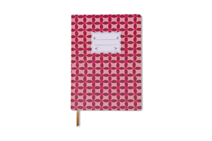 The Tulip Jumbo Journal - Pinwheel Pink features a repeating red geometric pattern, a white front label, and a brown ribbon bookmark. This floral-inspired journal stands out on a crisp white background.