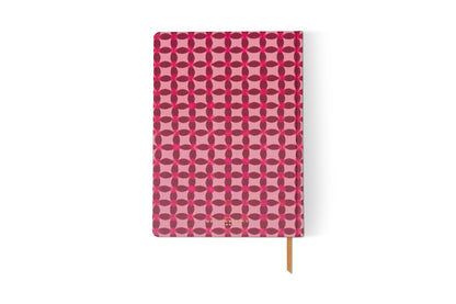 The Tulip Jumbo Journal - Pinwheel Pink has a pink cover with a red geometric floral pattern and an orange ribbon bookmark—perfect for capturing your thoughts in style.