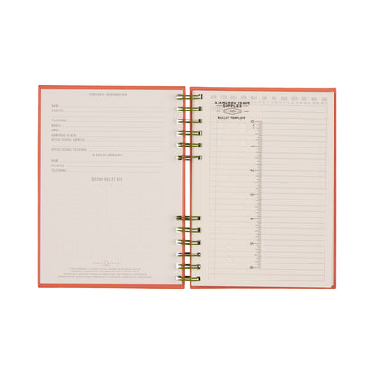 An open Standard Issue Planner Notebook No. 12 – Army Green + Chili, crafted with high-quality construction, reveals a personal information page on the left and a daily schedule template spanning 6 AM to 9 PM on the right, complete with note sections and a stamped inbox—delivering a premium writing experience reminiscent of the Standard Issue Notebook.