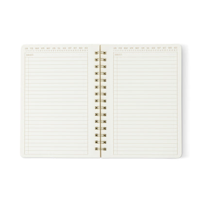The Textured Paper Twin Wire Notebook - Small Lilac is an open softcover notebook with lined, textured white pages, each featuring a Subject header and small Jan–Dec month abbreviations along the top edge.