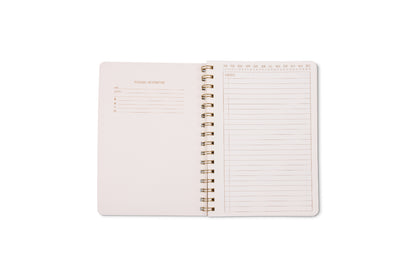 An open Tulip Small Twin Wire Notebook - Pinwheel Pink displays twin-wire binding, a personal info section on the left, and lined perforated pages with a date header for notes on the right, all on a white background.