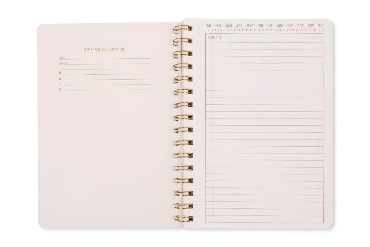 An open Tulip Twin Wire Notebook - Small Green Lattice shows a personal info section on the left page and a lined notes page with months labeled at the top on the right, all in a stylish twin-wire design.
