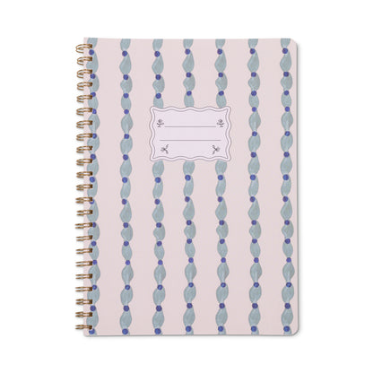 Introducing the Tulip Twin Wire Notebook - Large Wavy Blue: a spiral-bound notebook with a pink cover adorned with vertical blue wavy stripes and a central white label for adding your name or subject. This stylish twin-wire notebook features lined, perforated pages for easy and clean note removal.