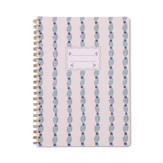 Introducing the Tulip Twin Wire Notebook - Large Wavy Blue: a spiral-bound notebook with a pink cover adorned with vertical blue wavy stripes and a central white label for adding your name or subject. This stylish twin-wire notebook features lined, perforated pages for easy and clean note removal.