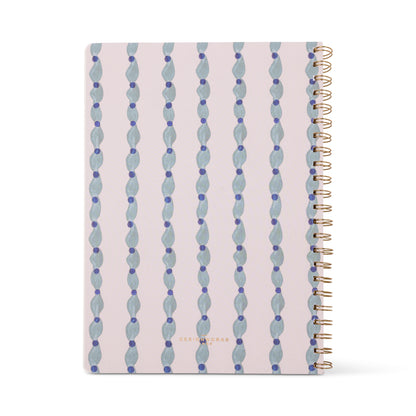 The Tulip Twin Wire Notebook - Large Wavy Blue is spiral-bound with a pale pink cover featuring blue and lavender wavy shapes, lined perforated pages, and "DESIGNWORKS" printed in gold at the bottom center.