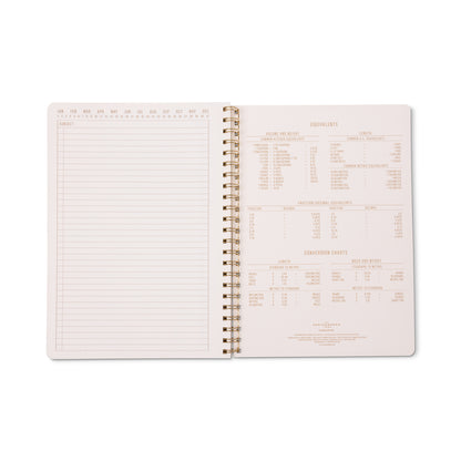 The Tulip Twin Wire Notebook - Large Orange Check lies flat when open, revealing a lined page with calendar months at the top left and measurement conversion charts, equivalents, and other reference information on the right.