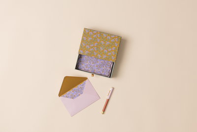 Notebook with a patterned cover, matching envelope, and pen on a beige background