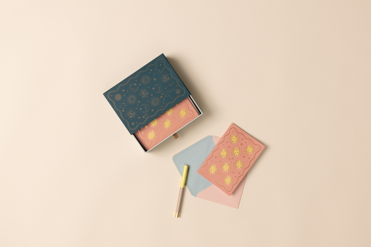 Boxed notecard set with floral designs on a beige background